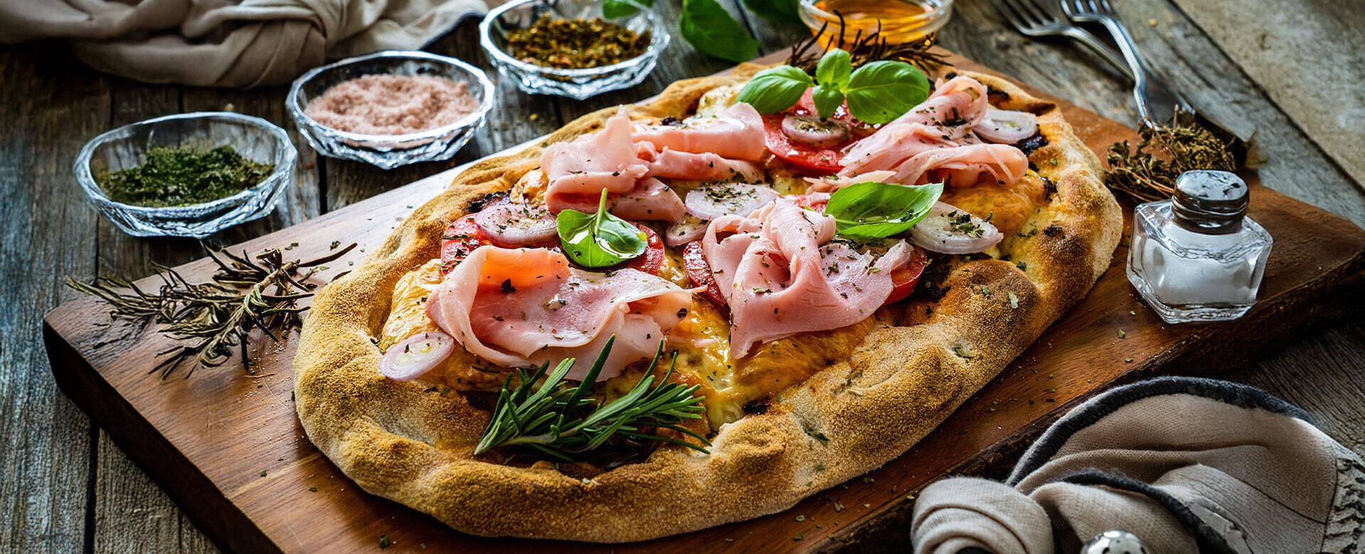 Pinsa mit Tomatensauce, Schinken, Basilikum, Zwiebel und Käse 
