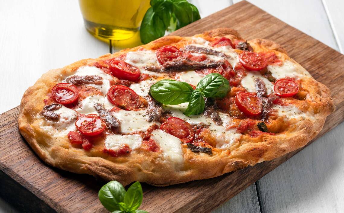 Pinsa mit Tomatensauce, Mozzarella, Sardellen und Tomaten 