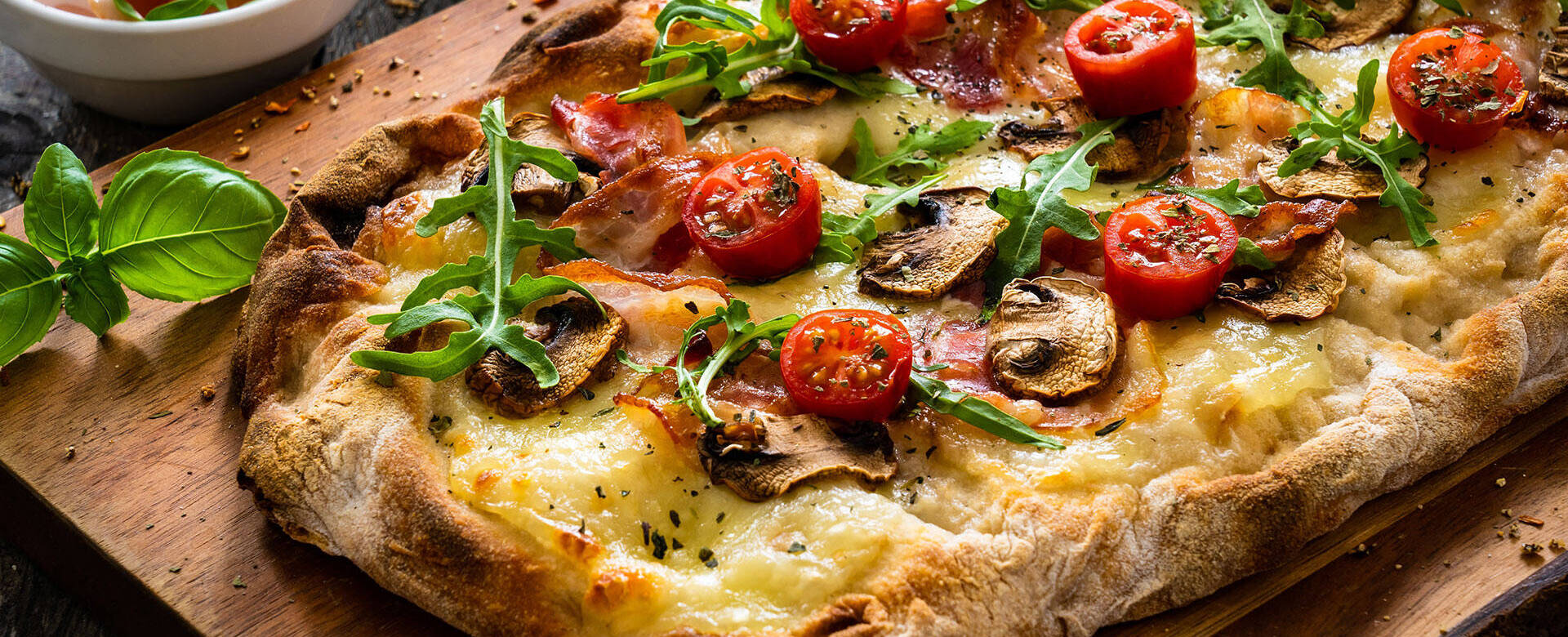 Pinsa mit Käse, Tomaten, Champignons und Rucola 